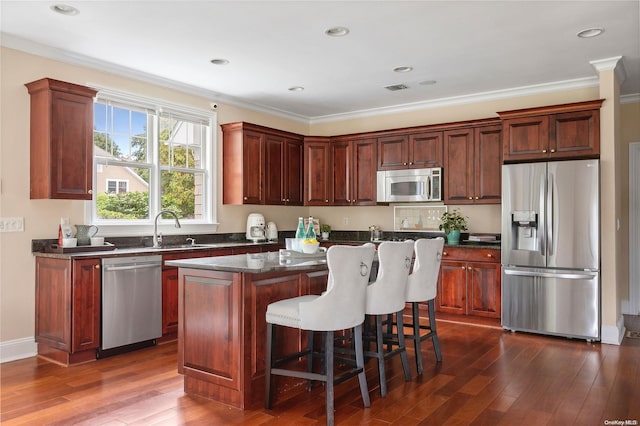 kitchen with a kitchen island, crown molding, stainless steel appliances, and dark wood-type flooring