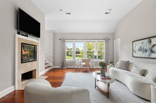 living room featuring hardwood / wood-style flooring, a tile fireplace, and vaulted ceiling