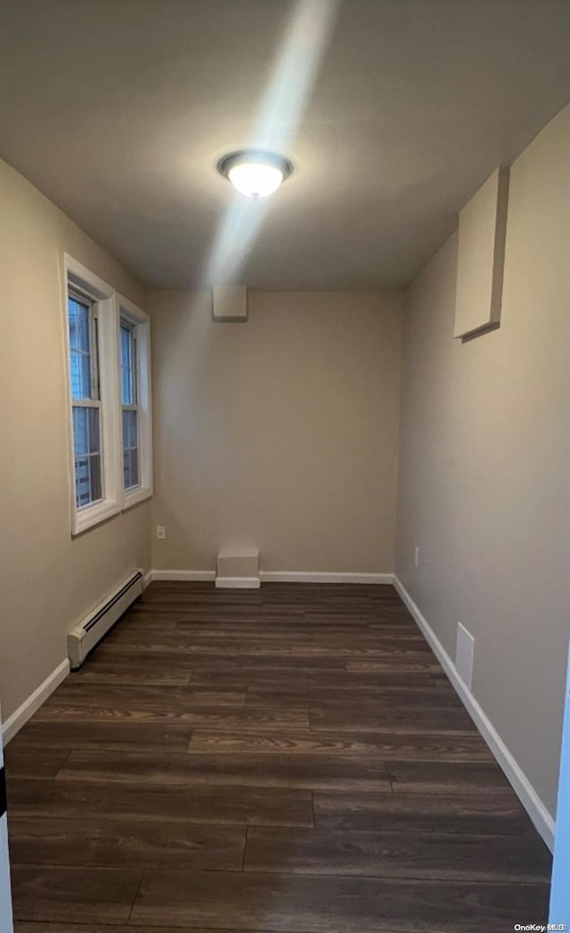 basement with dark hardwood / wood-style floors and a baseboard heating unit