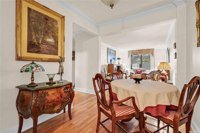 dining space with light wood-type flooring and ornamental molding