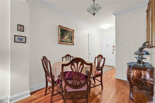 dining room with crown molding and light hardwood / wood-style flooring