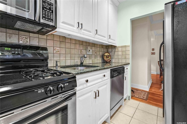 kitchen featuring white cabinets, light wood-type flooring, stainless steel appliances, and dark stone countertops