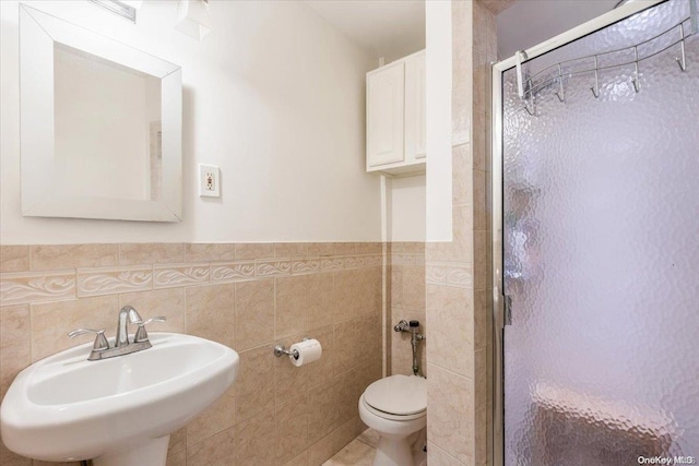 bathroom with toilet, sink, walk in shower, and tile walls