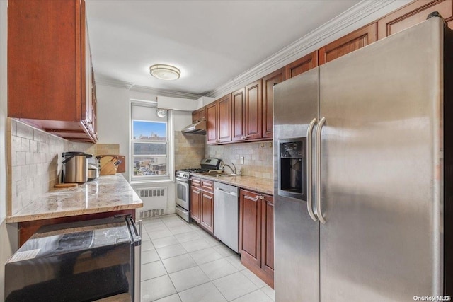 kitchen with backsplash, appliances with stainless steel finishes, light tile patterned flooring, light stone counters, and radiator heating unit