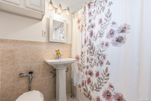 bathroom featuring toilet and tile walls