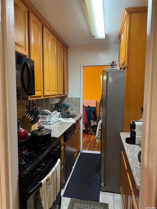 kitchen featuring light stone countertops, light hardwood / wood-style floors, and black appliances