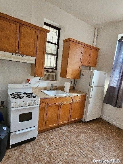 344 W 48 Unit 1Re, New York Manhattan, NY 10036 - kitchen with white appliances, a sink, ventilation hood, brown cabinets, and light countertops