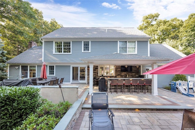 rear view of house featuring a patio and an outdoor bar