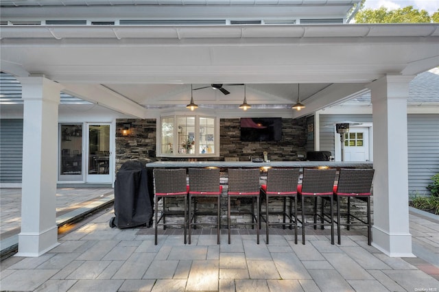 view of patio with ceiling fan and an outdoor bar