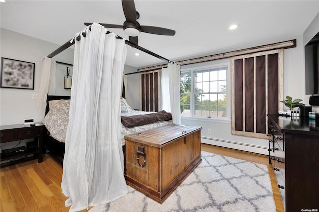 bedroom featuring light hardwood / wood-style floors, a baseboard radiator, and ceiling fan