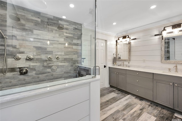 bathroom with tiled shower, vanity, and hardwood / wood-style flooring