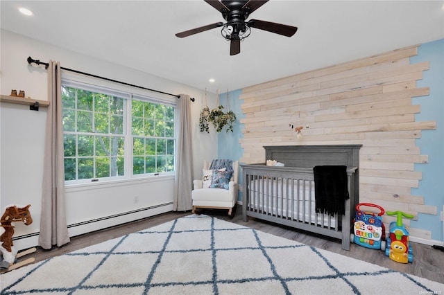 bedroom featuring ceiling fan, a crib, and dark wood-type flooring