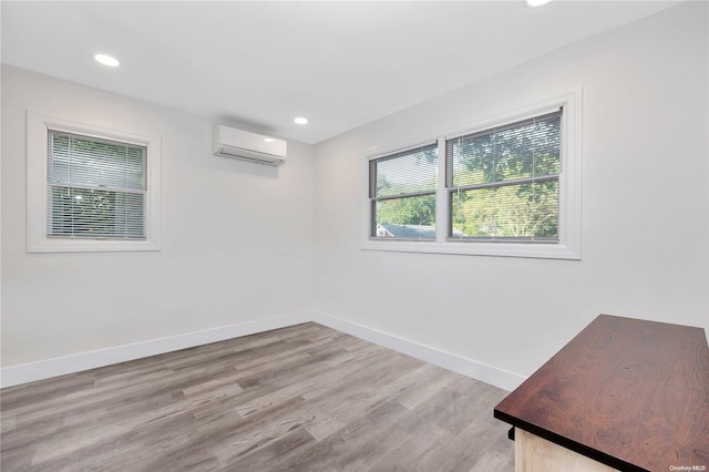 spare room with a wall mounted air conditioner and light wood-type flooring