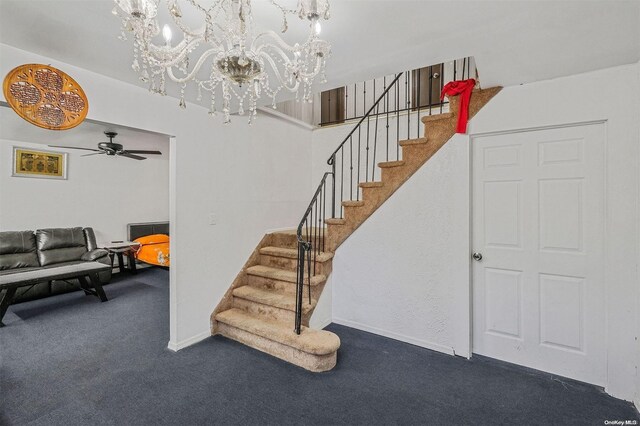 stairway featuring carpet flooring and ceiling fan with notable chandelier