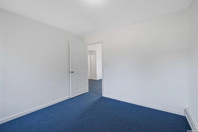 unfurnished room with dark colored carpet and a baseboard heating unit