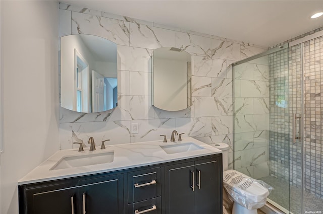 bathroom featuring vanity, toilet, a shower with door, and backsplash