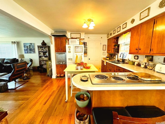 kitchen with white fridge with ice dispenser, sink, dark hardwood / wood-style floors, a notable chandelier, and kitchen peninsula