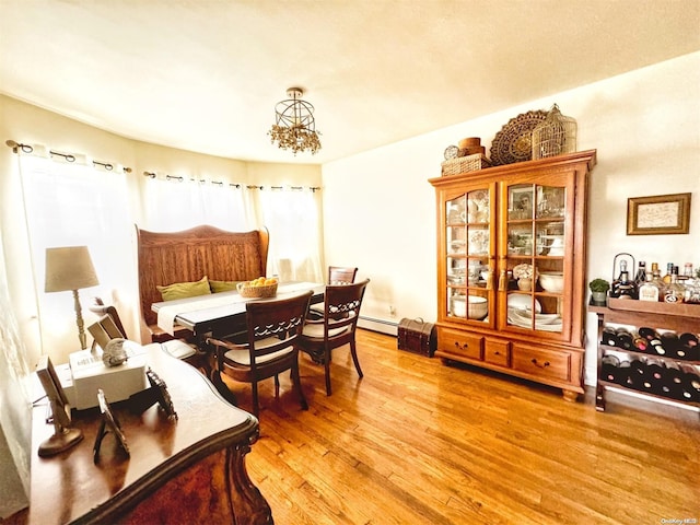 dining space featuring a chandelier, a baseboard heating unit, and hardwood / wood-style flooring