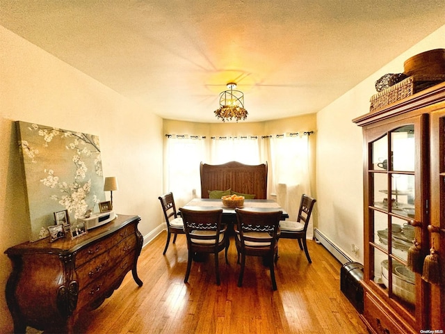 dining area with wood-type flooring, a textured ceiling, and a baseboard heating unit