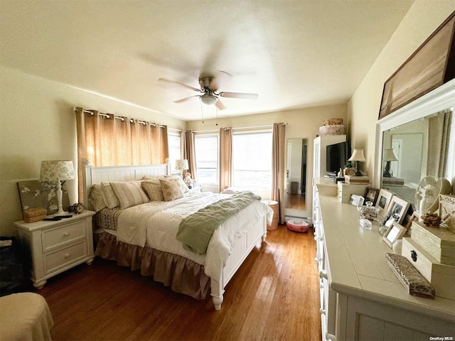 bedroom with ceiling fan, wood-type flooring, and a baseboard heating unit