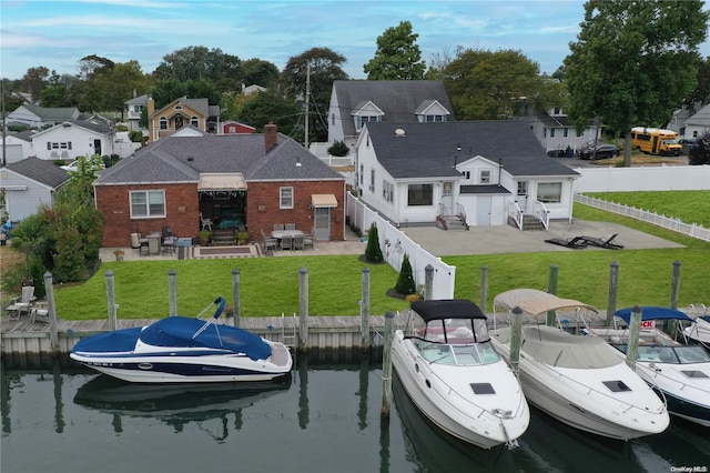 view of dock with a patio, a water view, and a lawn