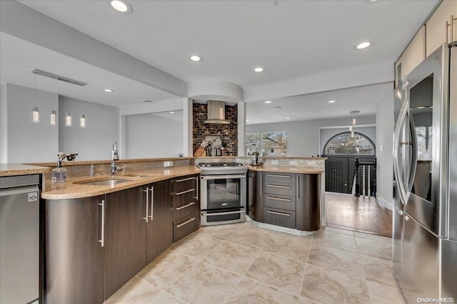 kitchen featuring dark brown cabinetry, sink, stainless steel appliances, light stone counters, and decorative light fixtures