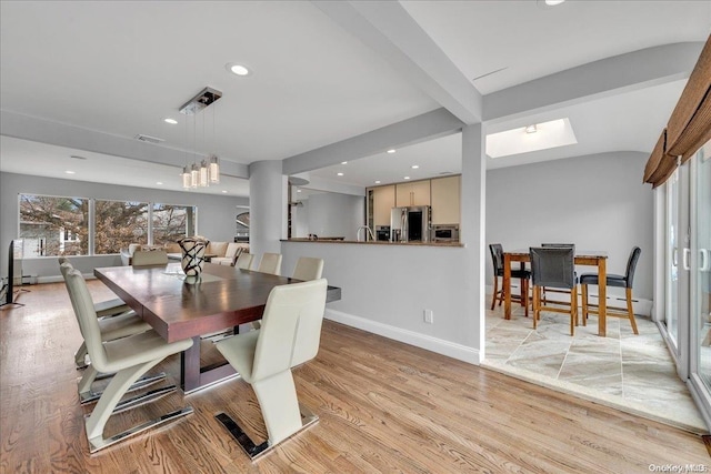 dining room featuring an inviting chandelier, beam ceiling, and light hardwood / wood-style flooring