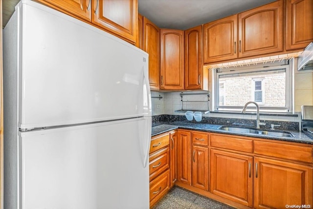 kitchen featuring white refrigerator, backsplash, dark stone counters, and sink