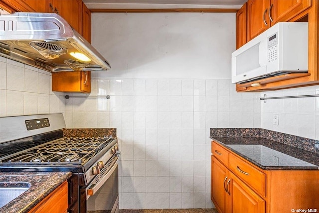 kitchen with stainless steel gas stove, extractor fan, tile walls, and dark stone counters