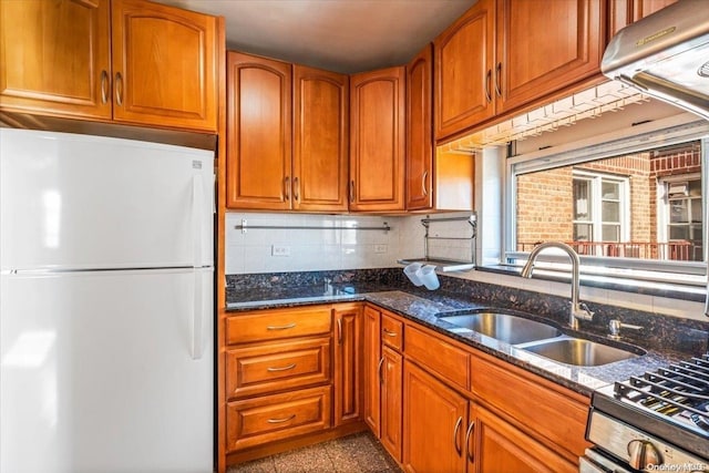 kitchen with backsplash, white refrigerator, sink, dark stone countertops, and stainless steel range