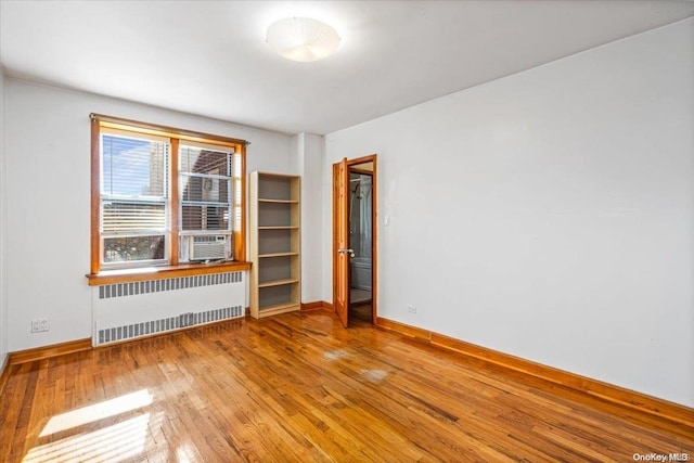 spare room featuring radiator heating unit, light hardwood / wood-style floors, and cooling unit