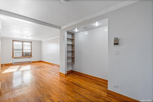 unfurnished living room featuring hardwood / wood-style flooring, cooling unit, crown molding, and radiator