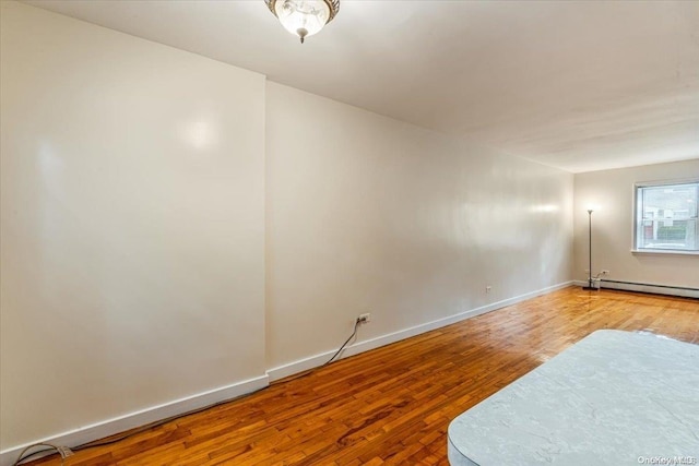 spare room featuring wood-type flooring and a baseboard radiator