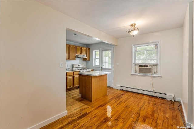 kitchen with cooling unit, a baseboard heating unit, wood-type flooring, a center island, and stainless steel stove