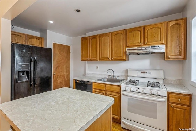 kitchen with black appliances, a kitchen island, light wood-type flooring, and sink