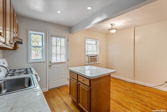 kitchen with light hardwood / wood-style flooring, a kitchen island, plenty of natural light, and sink