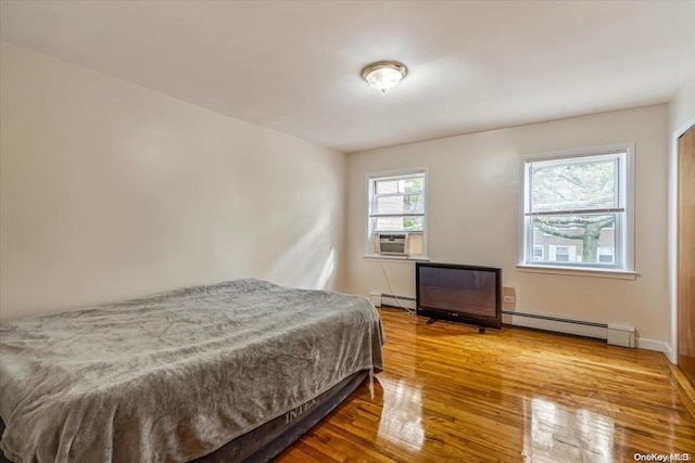 bedroom with a baseboard radiator, hardwood / wood-style flooring, and cooling unit