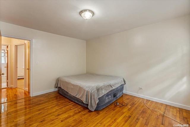 bedroom featuring hardwood / wood-style floors and a baseboard radiator