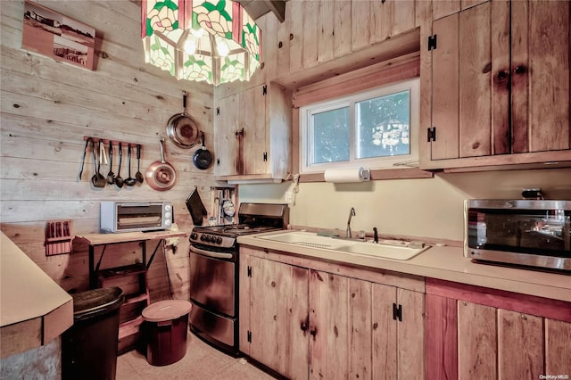 kitchen featuring stainless steel appliances, wood walls, and sink