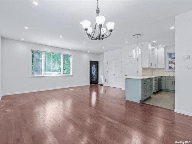 unfurnished living room featuring beverage cooler, light hardwood / wood-style floors, and a notable chandelier