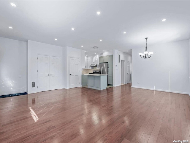 unfurnished living room with wood-type flooring and an inviting chandelier