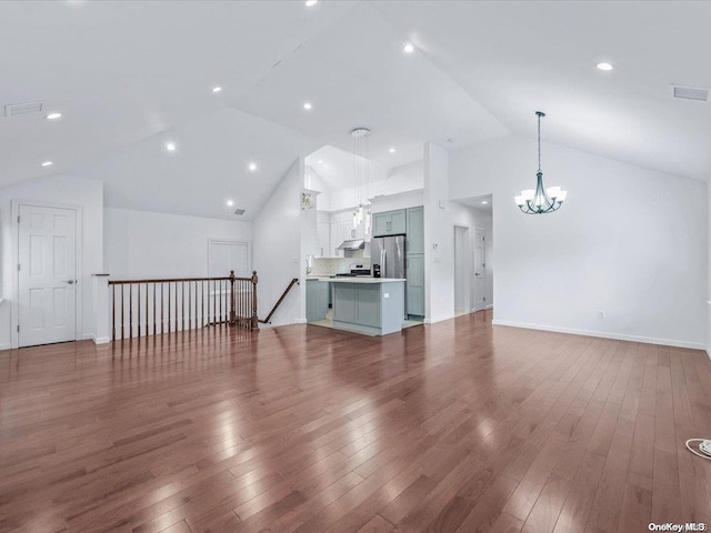 unfurnished living room featuring hardwood / wood-style flooring, high vaulted ceiling, and a notable chandelier