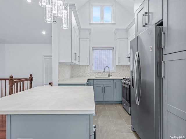 kitchen featuring pendant lighting, lofted ceiling, sink, appliances with stainless steel finishes, and tasteful backsplash