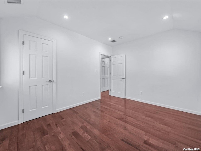 unfurnished bedroom featuring lofted ceiling and dark wood-type flooring