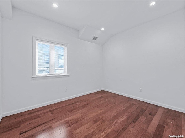 spare room featuring hardwood / wood-style flooring and vaulted ceiling