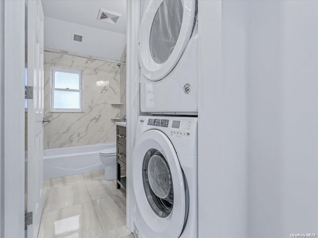 laundry room with light tile patterned floors and stacked washer / dryer