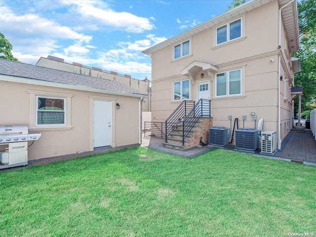 rear view of house featuring cooling unit and a lawn