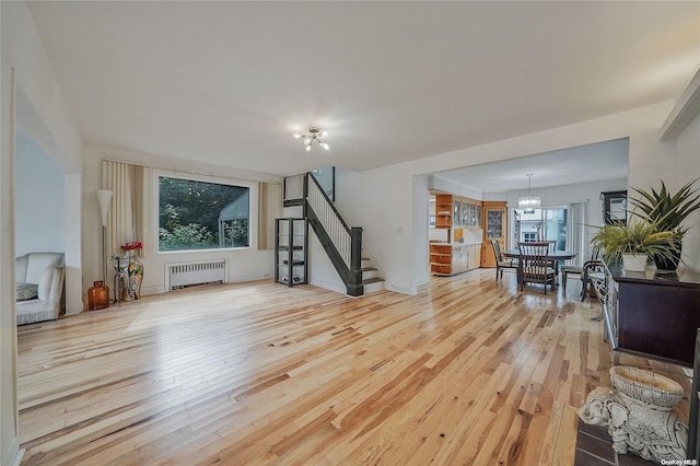 living room featuring a chandelier, a healthy amount of sunlight, radiator, and light hardwood / wood-style flooring