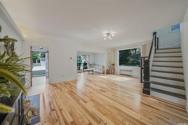 living room featuring radiator heating unit, light hardwood / wood-style flooring, and a healthy amount of sunlight