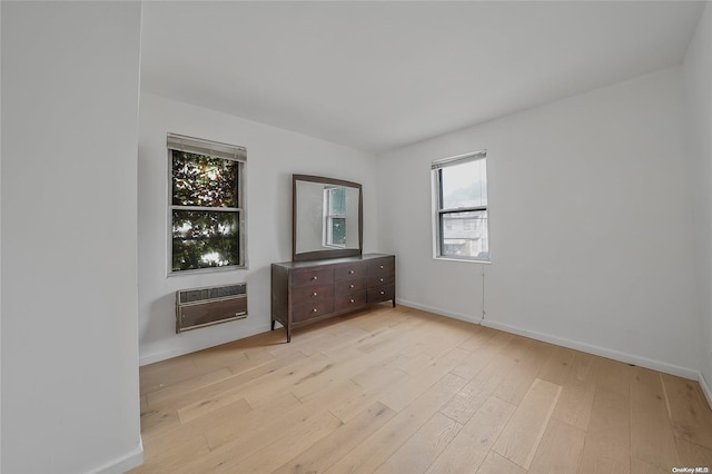 spare room featuring a healthy amount of sunlight, light wood-type flooring, and heating unit